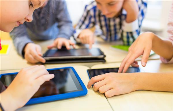 Group of students looking down at iPads on desks in classroom 